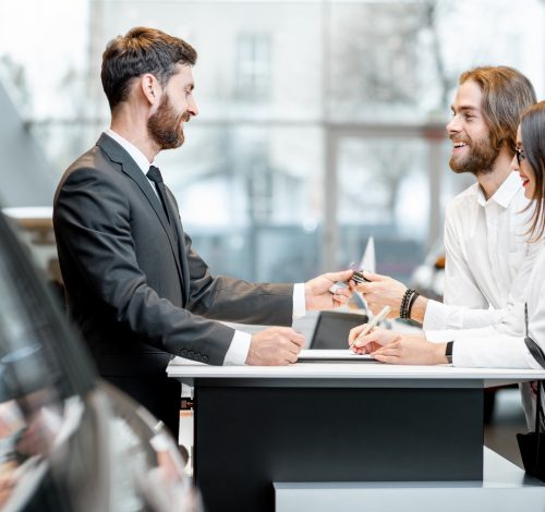 Business couple at the stand with salesperson in the showroom
